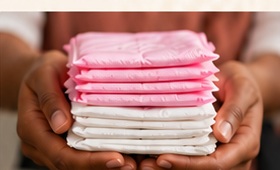 Hands holding a stack of menstrual products